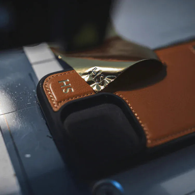 Close-up of a brown leather strap with a gold buckle on a dark surface