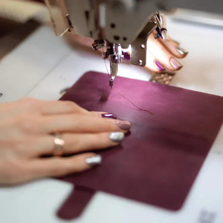 A leather phone case being stitched by han