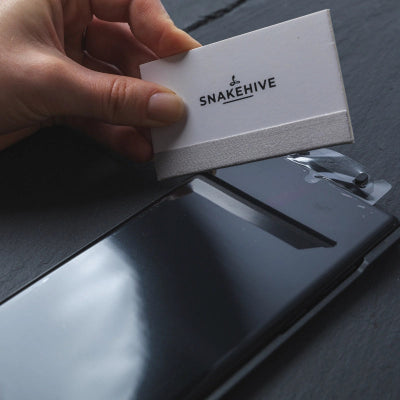 Hand holding a white card with 'Snakehive' logo on a reflective surface